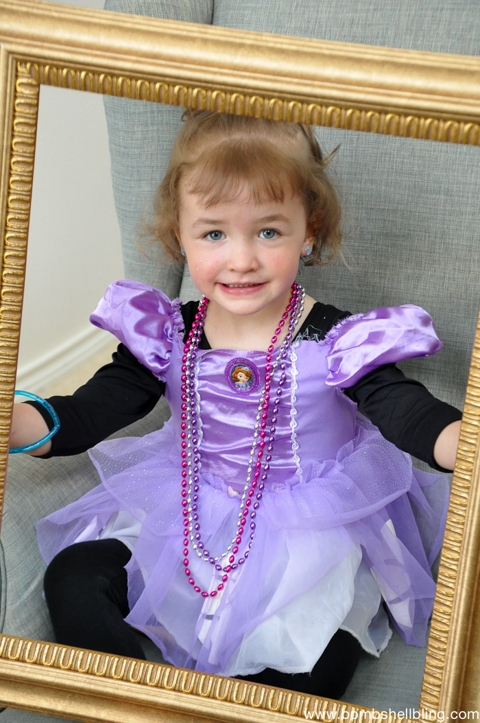Blonde girl in purple dress holding gold frame at Bippity Boppity Boutique Party