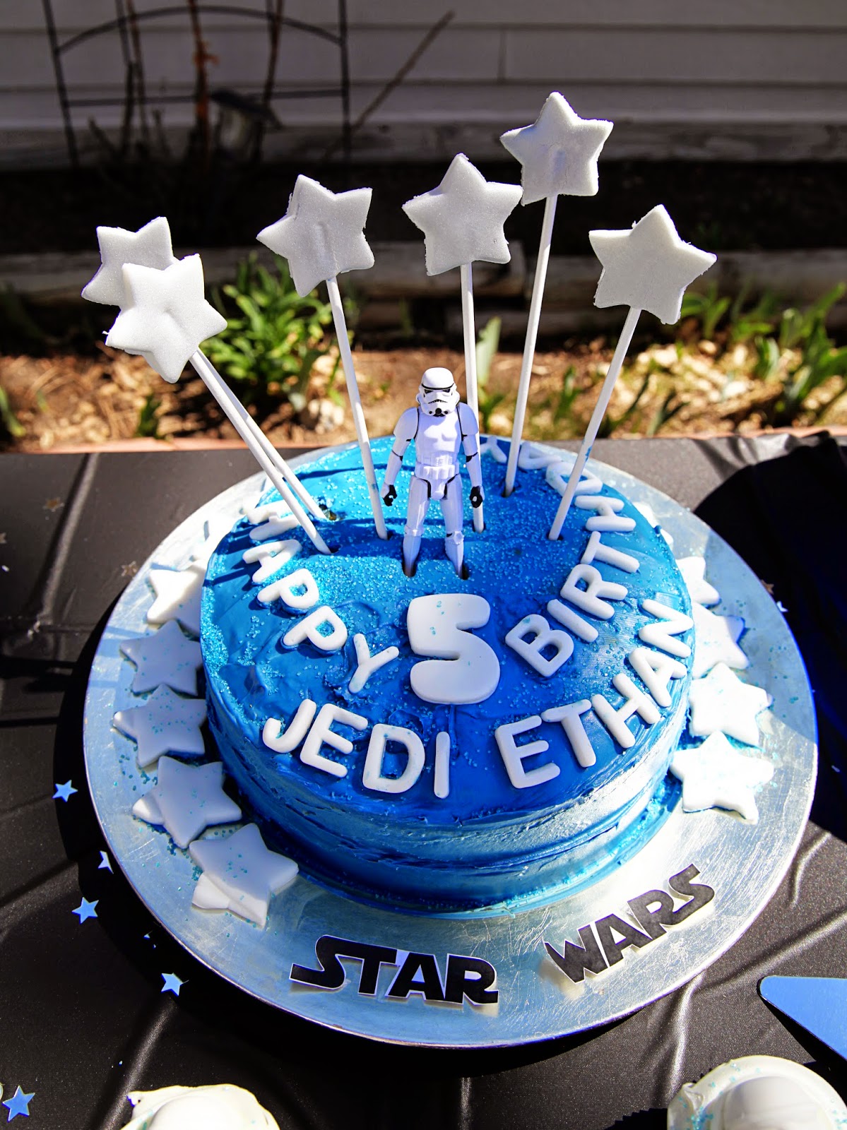 Star Wars Lego birthday cake with white star candles and Storm Trooper toy for topper