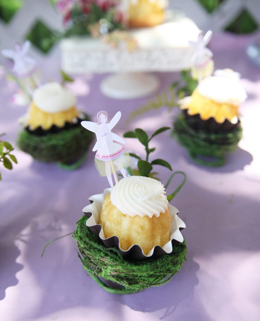 Vanilla cupcake in moss bird's nest on table at fairy birthday party